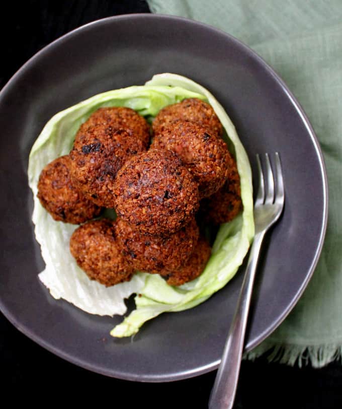 A mountain of perfectly cooked, golden vegan falafel in bowl with lettuce.