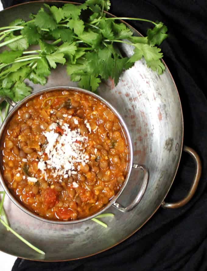 10-minute dal in a karahi inside a copper server with cilantro next to it and a coconut garnish.