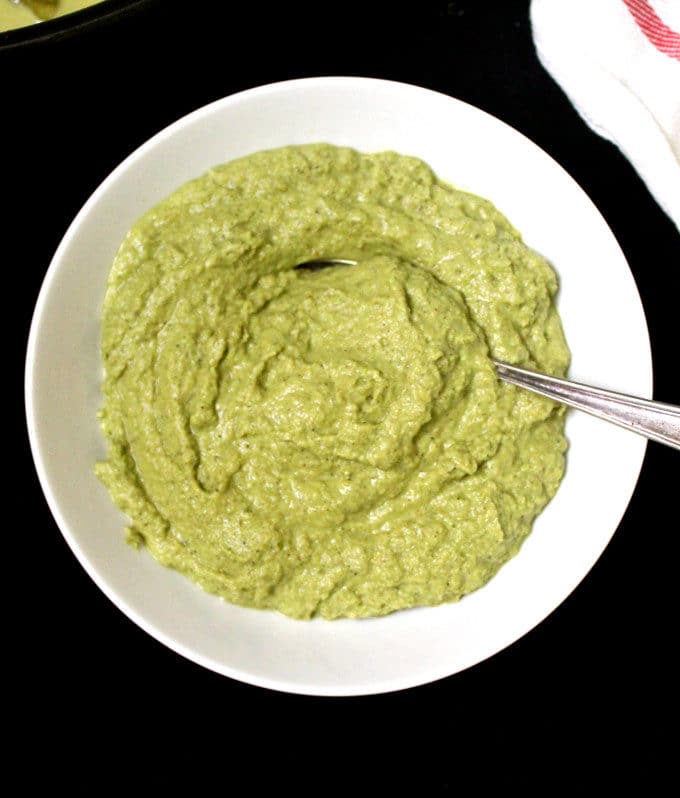 Top shot of the green curry paste in a white bowl with a spoon