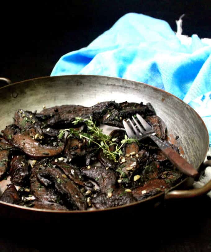 Vegan garlic butter mushrooms in a copper pan with fork and sprigs of thyme.