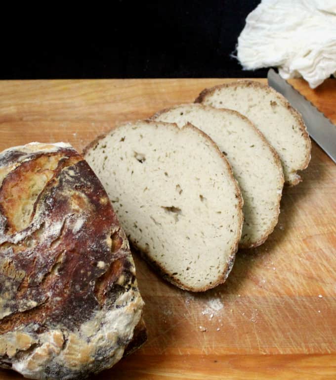 Gluten-free Sourdough Boule sliced on chopping board with knife.