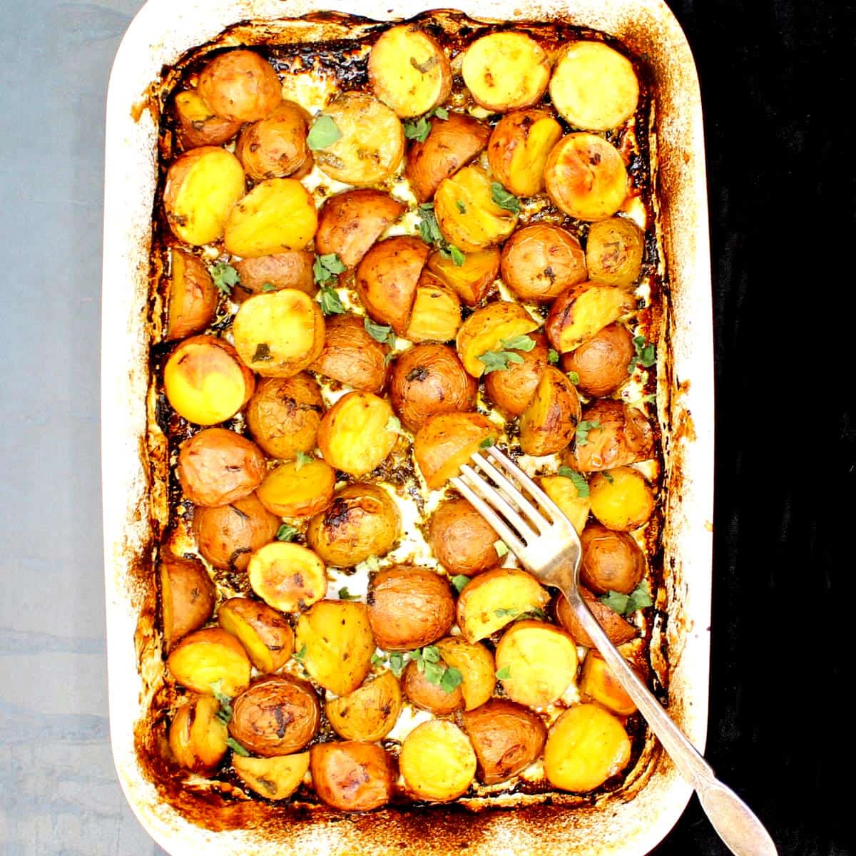 Greek lemon potatoes baked in baking dish with fork.