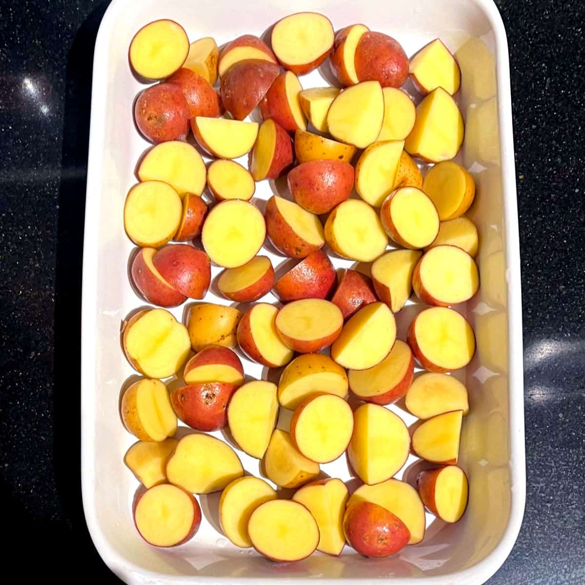 Raw potatoes arranged in single layer in baking dish.