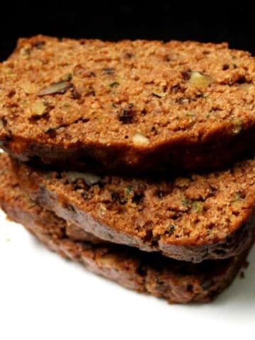 Slices of vegan zucchini bread stacked on a white plate.