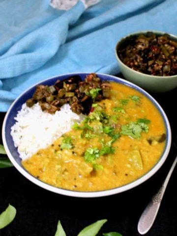 Green tomato dal in bowl with rice and sabzi on side.