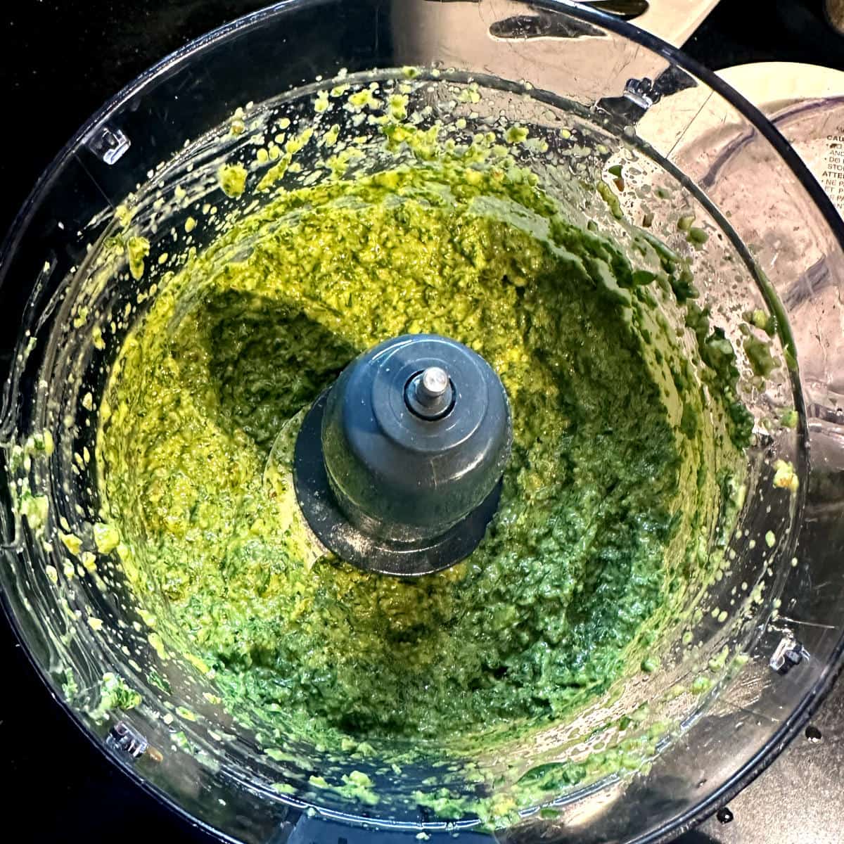 Photo of blended basil pesto in food processor bowl.