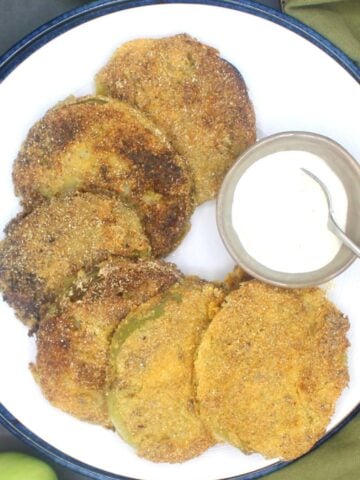 Vegan fried green tomatoes on white plate with remoulade.