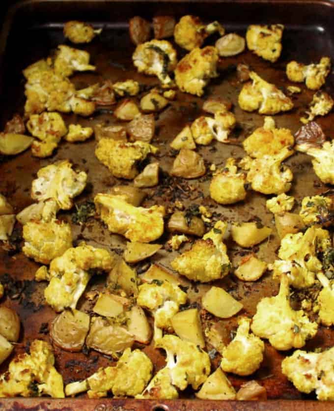 Curry roasted cauliflowers tossed with cilantro, coriander powder, cumin and turmeric on baking sheet.