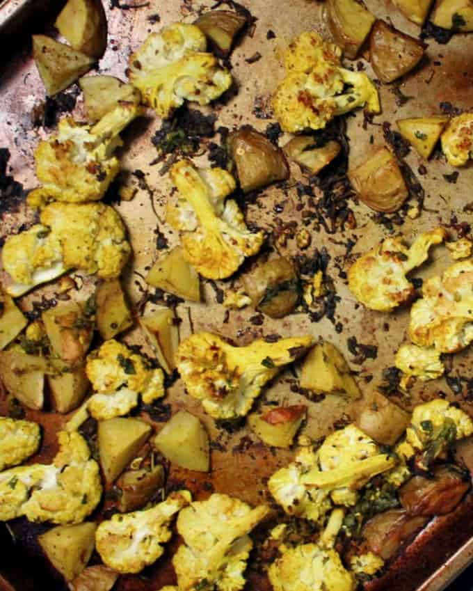 A close up of curry roasted cauliflower potatoes on baking sheet