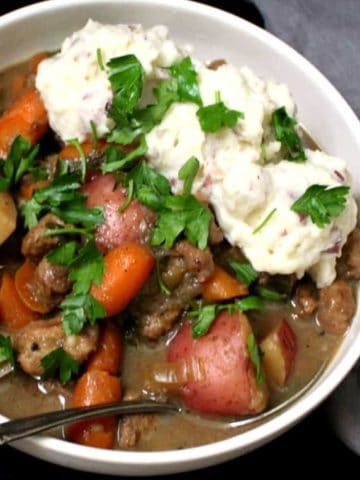 A bowl of vegan Irish stew with creamy mashed potatoes, carrots, celery and parsley