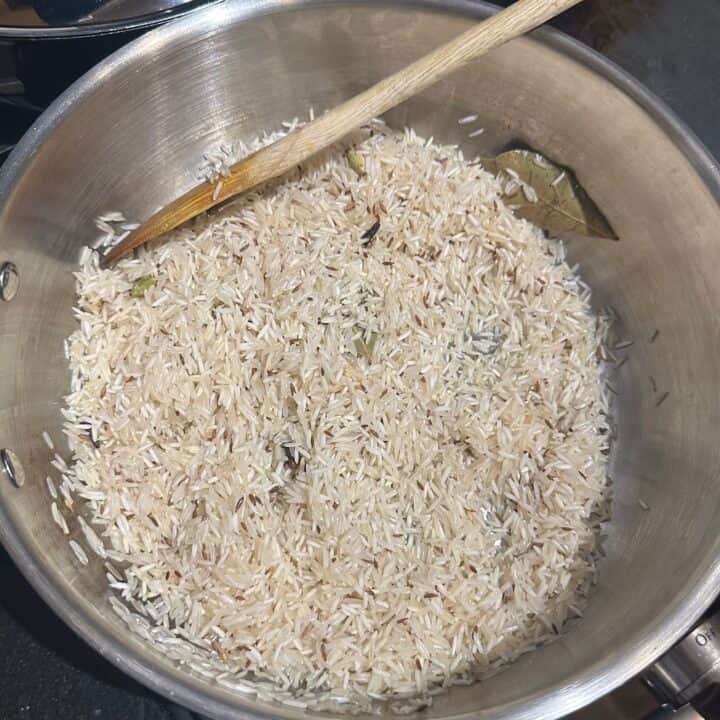 Rice sauteing with spices in pan.