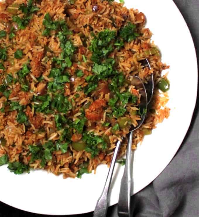 Top partial shot of a plate of dirty rice with vegan beyond meat sausage and parsley in a white platter