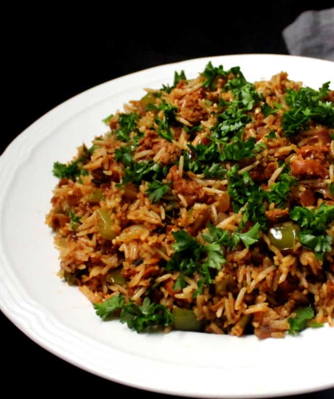 A partial shot of a white plate of dirty rice with parsley