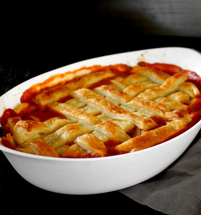 A vegan Guinness Pot pie with a golden, crispy puff pastry lattice top in a white oval baking dish