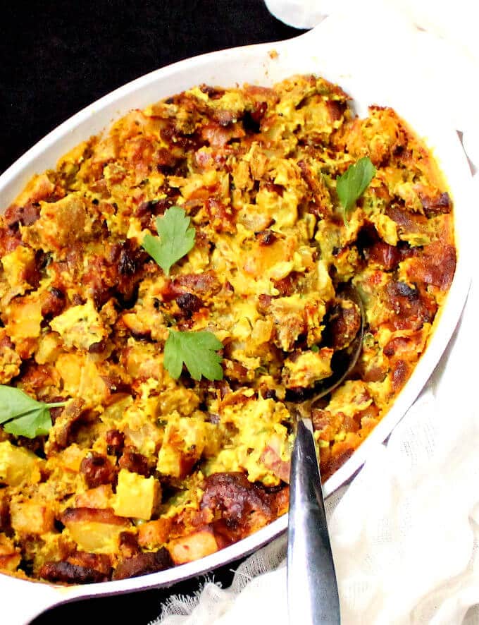 Vegan potato breakfast casserole in baking dish with steel spoon.