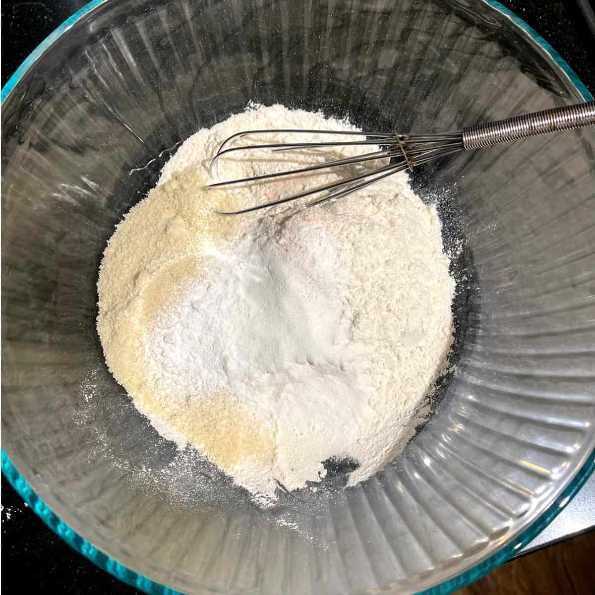 Dry ingredients with whisk in glass bowl.