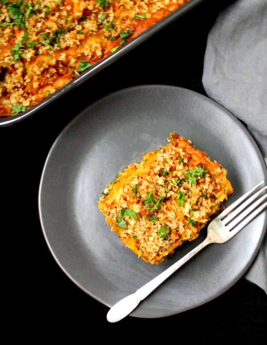 Overhead shot of a slice of vegan pumpkin lasagna with a fork and a baking pan in the background