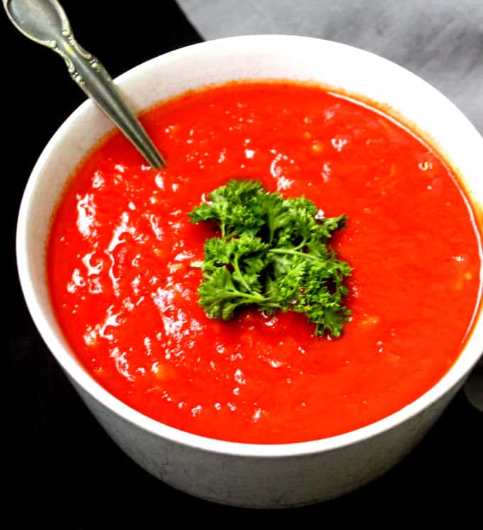 The best marinara sauce in a white bowl with parsley and a spoon.