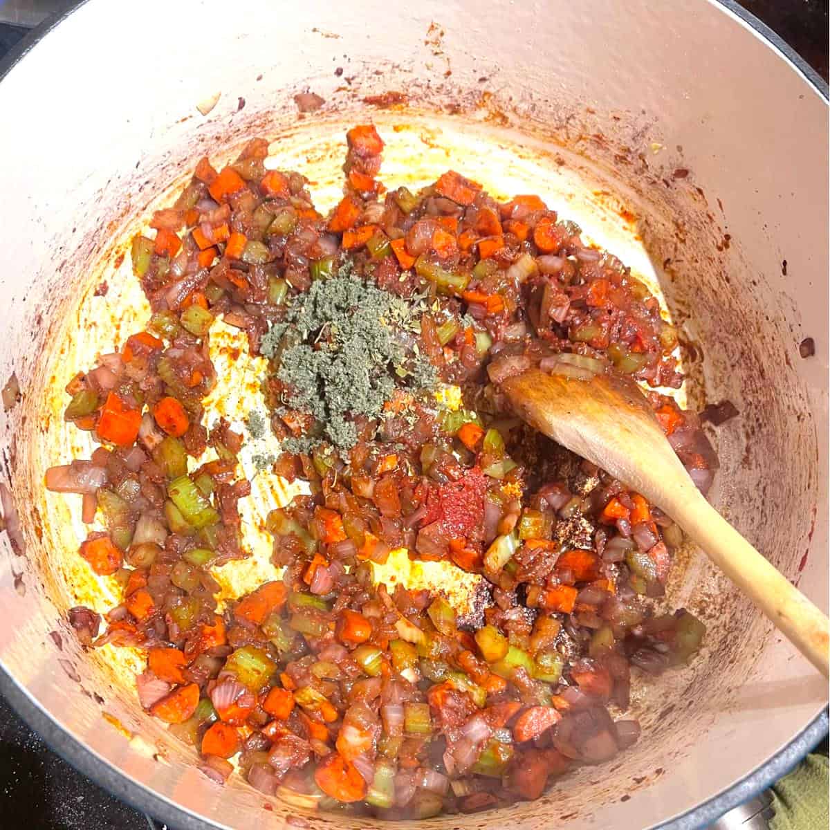 Herbs added to vegetables and tomato pastes in Dutch oven.