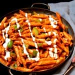 A front shot of Indian style pasta made with a red masala tomato sauce, green bell peppers and cashew cream