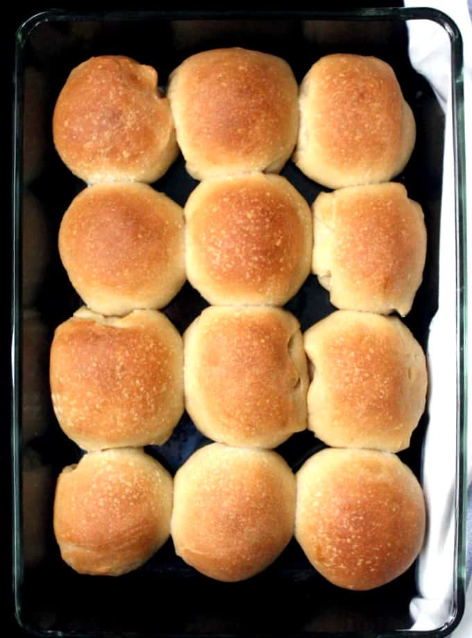 Twelve soft sourdough dinner rolls in a  glass baking pan
