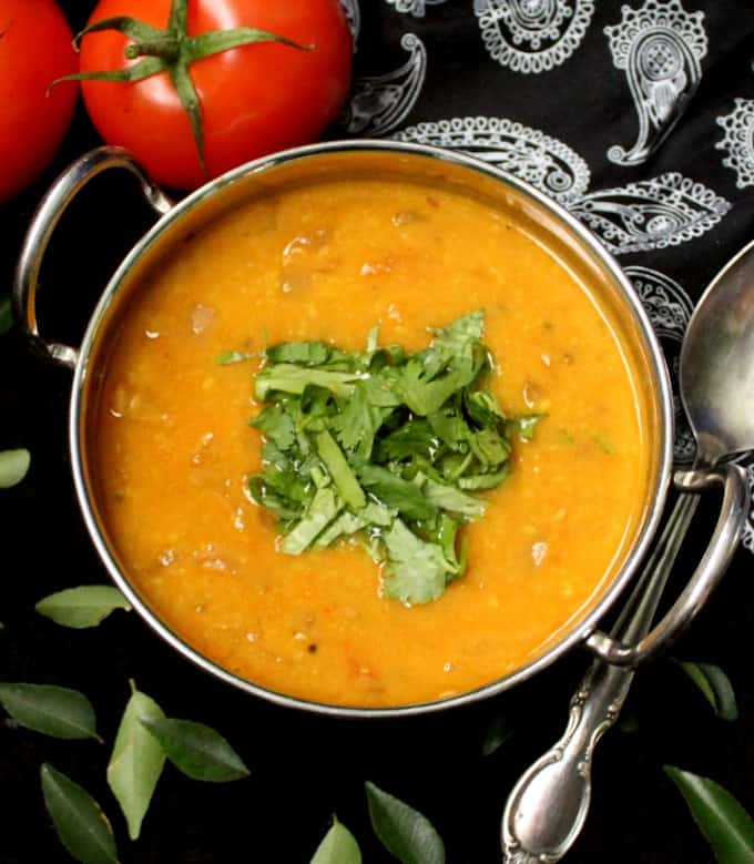 Overhead shot of tomato dal in a kadhai with a garnish of cilantro and curry leaves