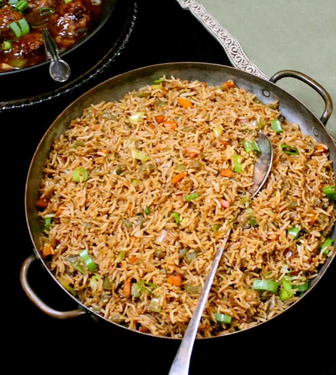 Overhead shot of a large server with veg fried rice with a silver serving spoon and green napkin