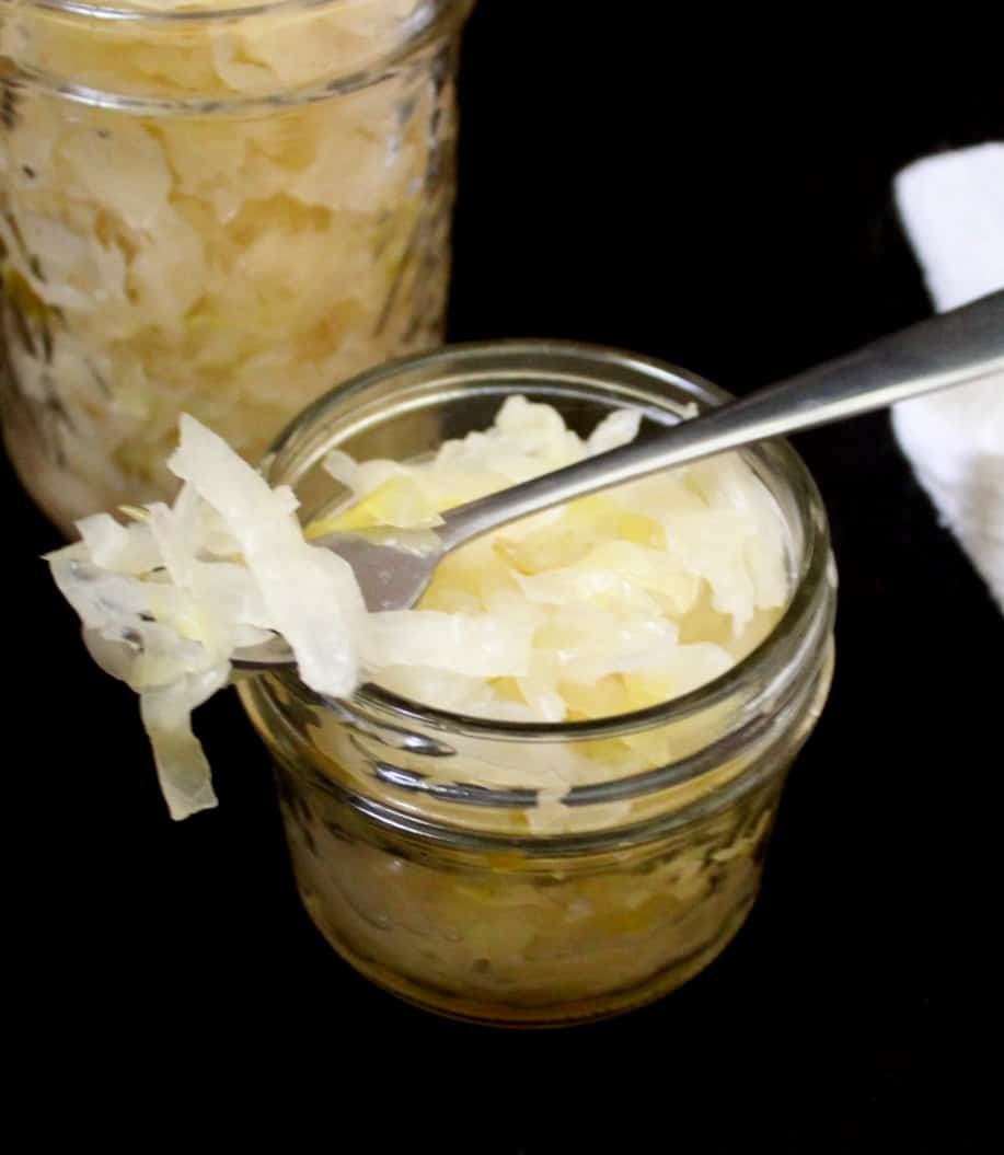 Close-up of a mason jar filled with sauerkraut with some shreds on a fork