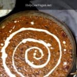 Vegan Dal Makhani in a copper serving dish with cumin rice and onions