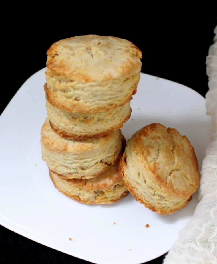 A stack of five flaky vegan sourdough biscuits on a white plate