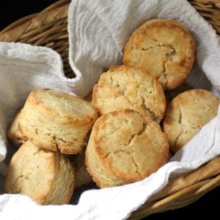 Close up shot of vegan sourdough biscuits nestled in a wicker basket with a flour sack napkin