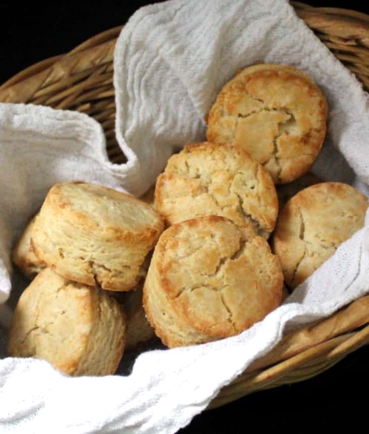 Vegan sourdough biscuits nestled in a wicker basket with a flour sack napkin