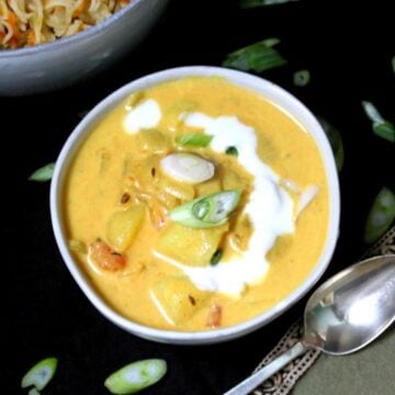 Coconut curry with scallion garnish and coconut milk in bowl.