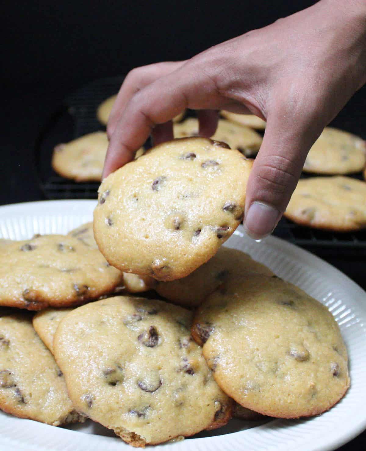 Jay's hand taking a chocolate chip sourdough cookie from a plate.
