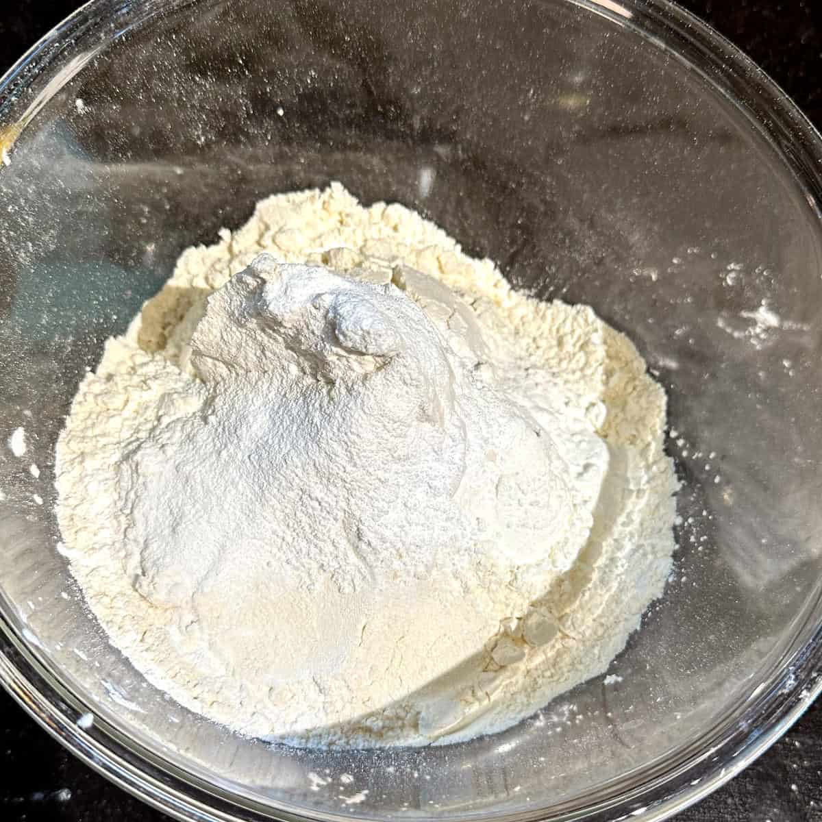 Flour, baking soda, baking powder and cardamom in bowl.