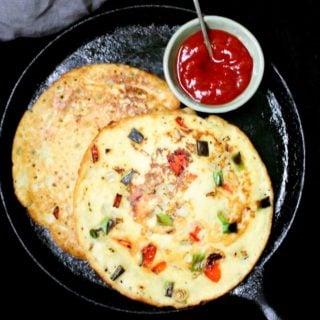 Moonglet, a mung bean omelet packed with veggies, on a cast iron griddle with sauce on the side