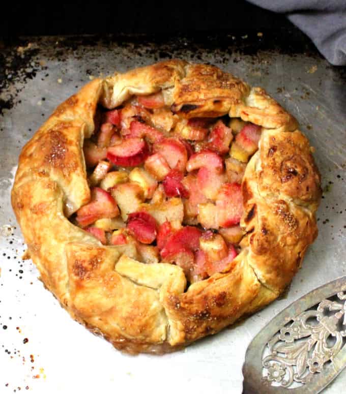 Shot of full vegan rhubarb galette on a baking sheet with a silver server