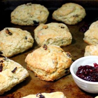 A closeup of several baked vegan cranberry sourdough scones on a baking sheet with raspberry jam