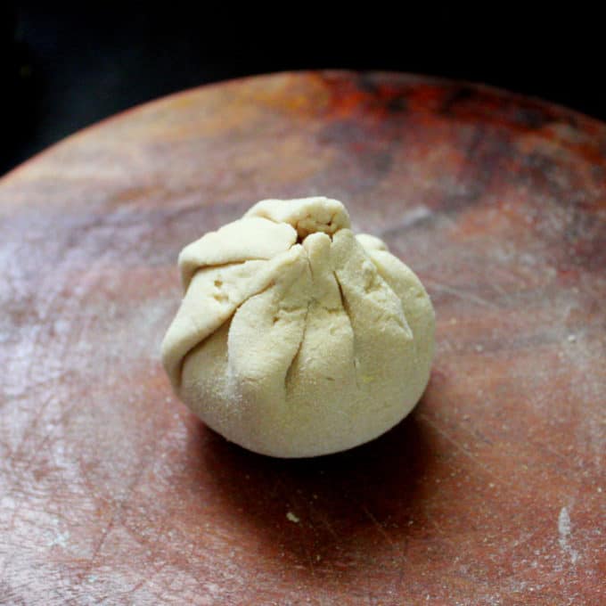 A ball formed with potato stuffing and whole wheat dough for aloo paratha waiting to be rolled