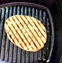 Gluten free naan with cross hatch pattern on grill.