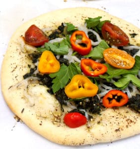 A colorful Manakish with spinach, za'atar. sweet peppers and cherry tomatoes on a white background