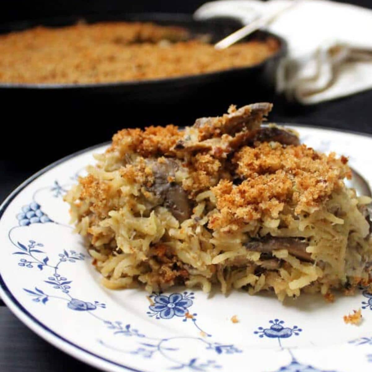 Vegan mushroom rice casserole in dish with cast iron pan in background.