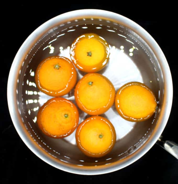 Clementines boiling in water in a saucepan.