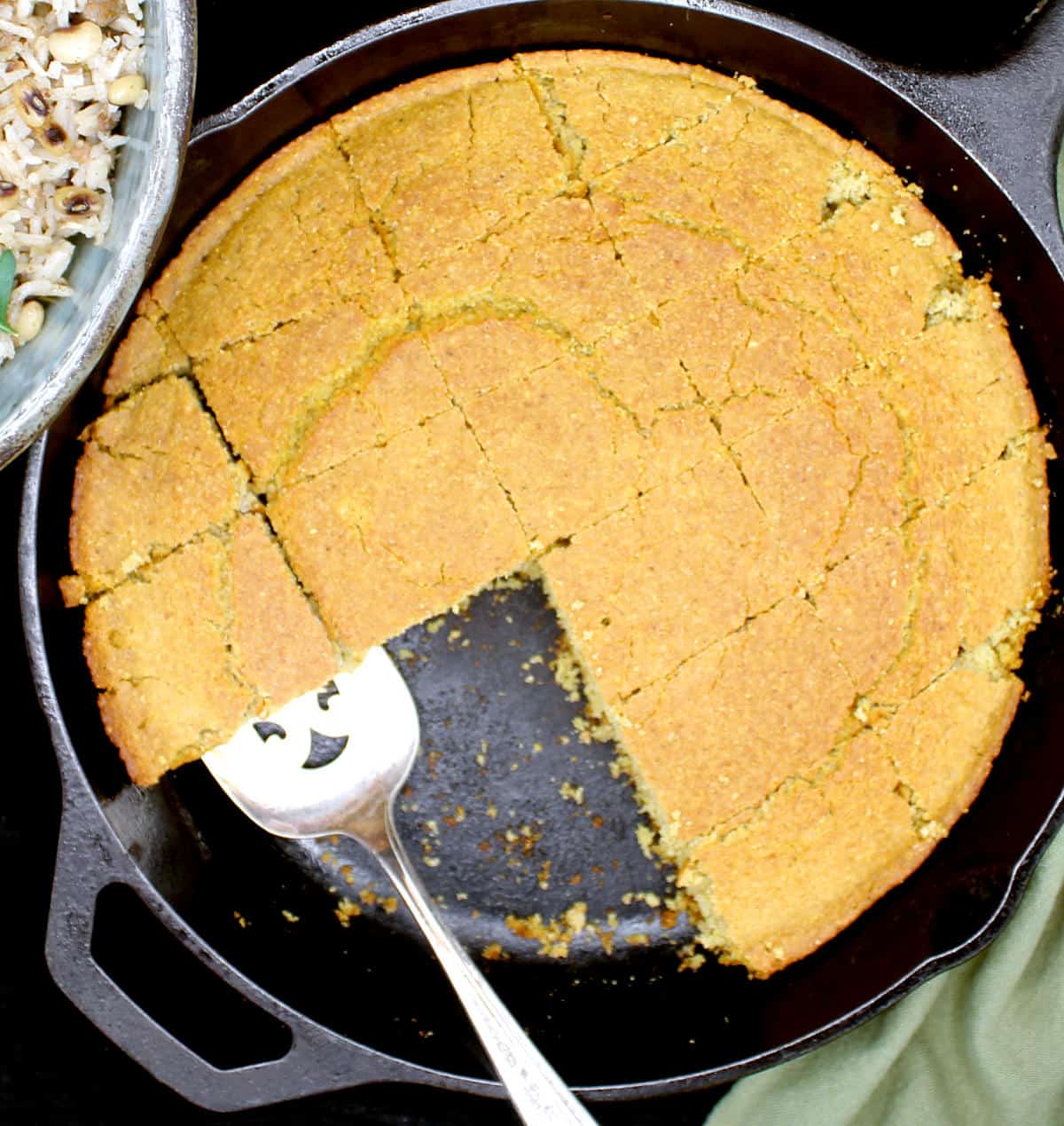 A cast iron skillet with cornbread squares cut out.