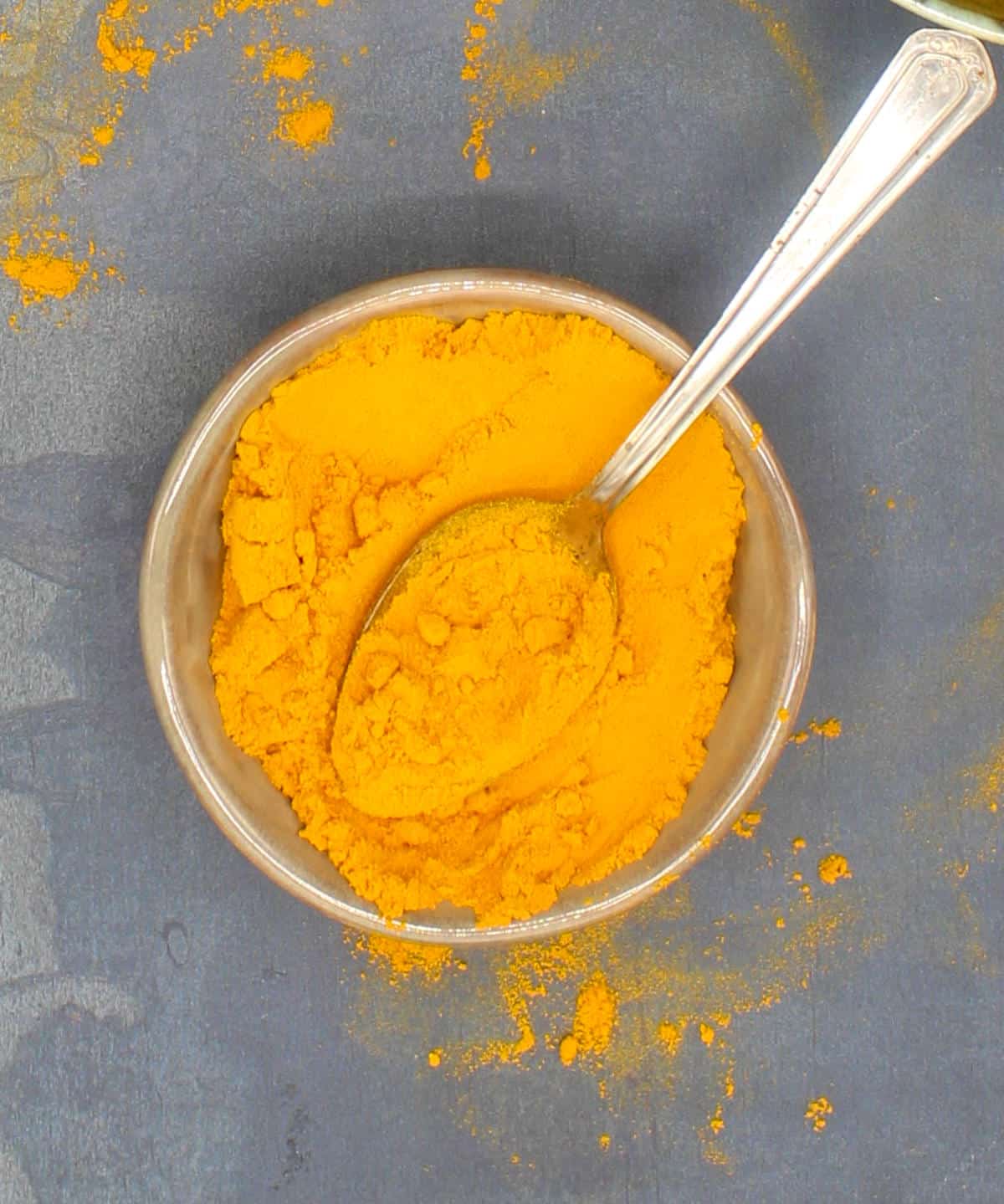 Ground turmeric in a bowl with spoon