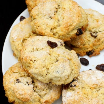 A stack of fluffy vegan currant scones in a white plate with black currants or raisins