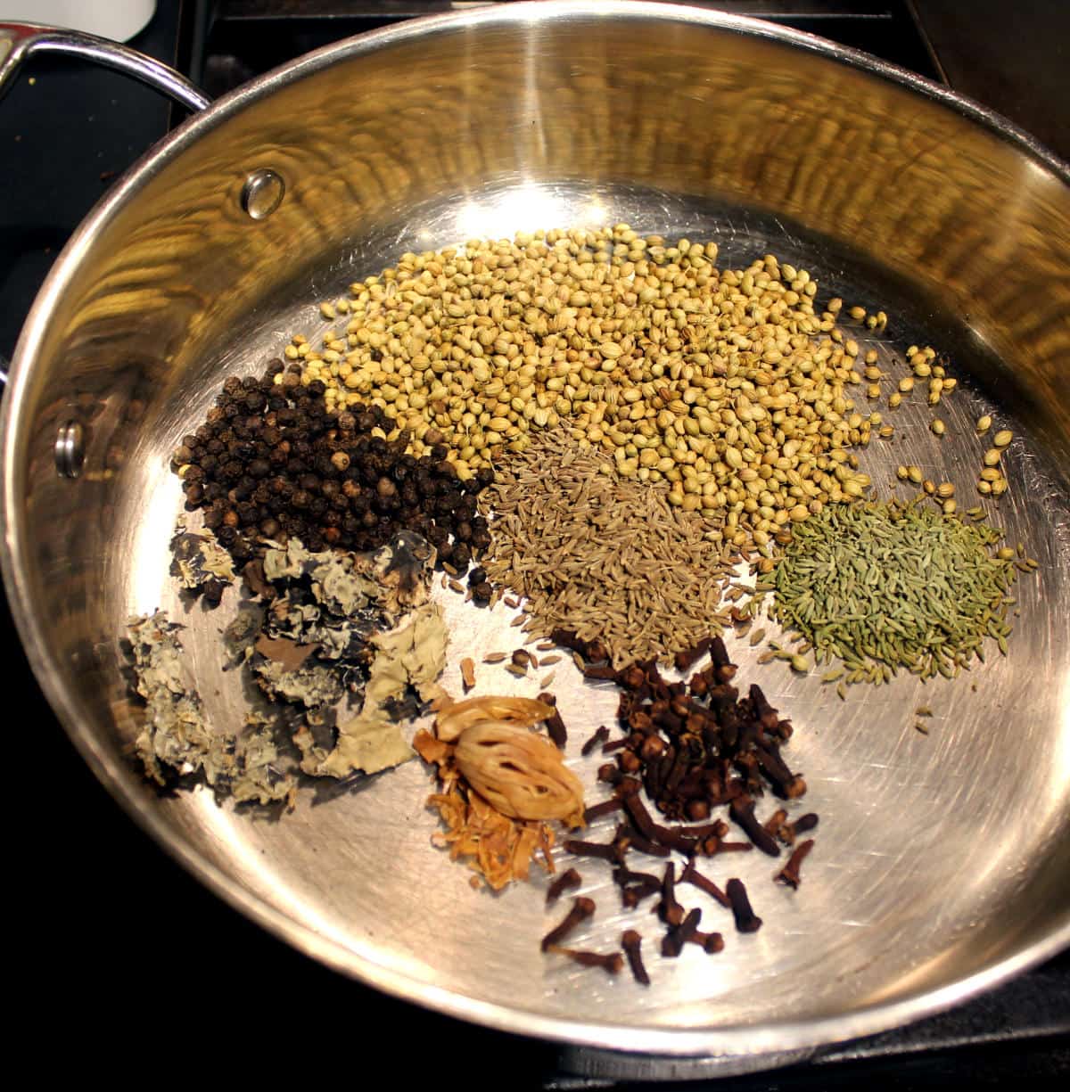 Coriander seeds, pepper, cumin, mace, cloves and pepper added to a skillet.