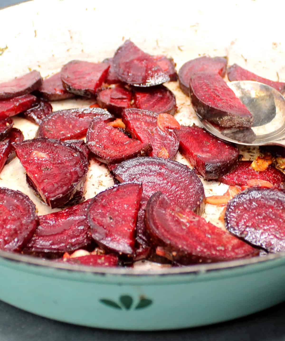Close up of slices of deep red beetroot tossed with garlic and butter in a skillet.