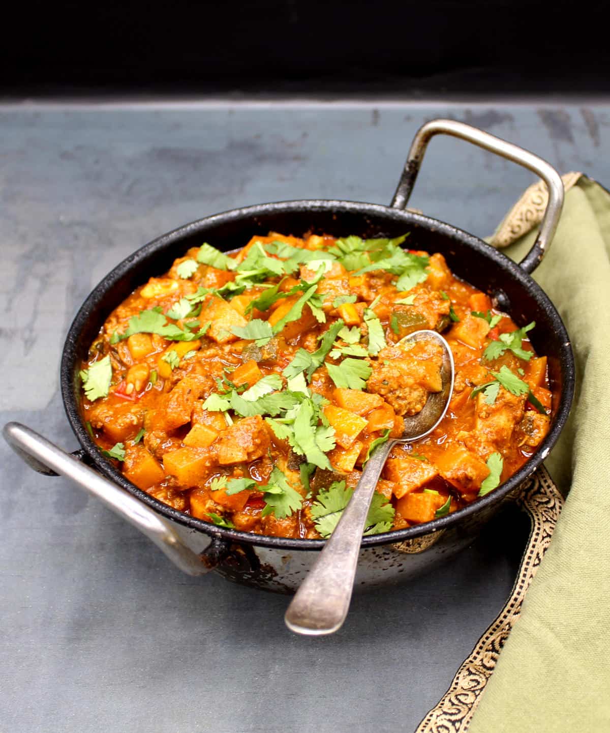 Vegan indian curry in karahi with spoon.