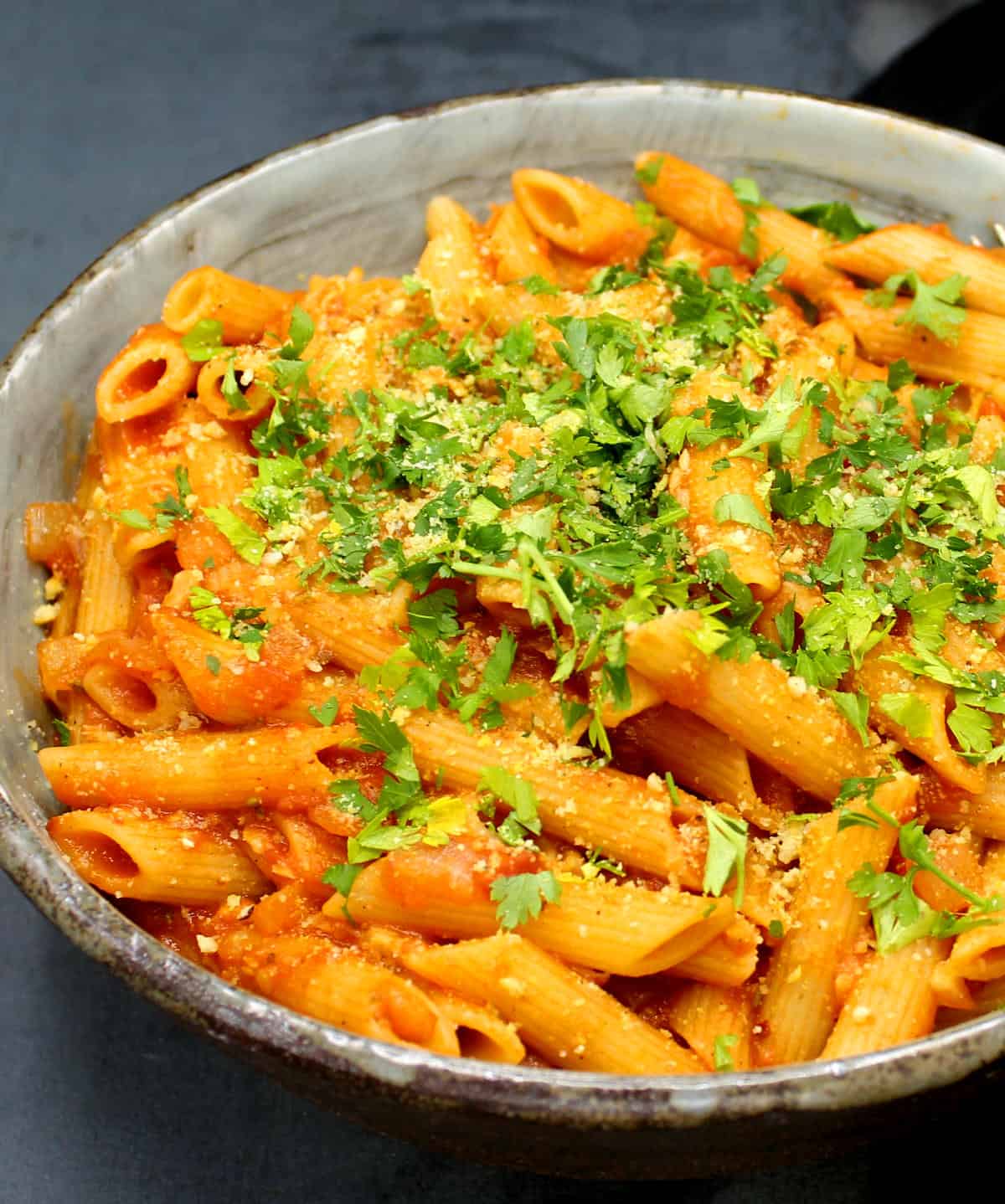 A big bowl of vegan pasta amatriciana with parsley and cashew parmesan.